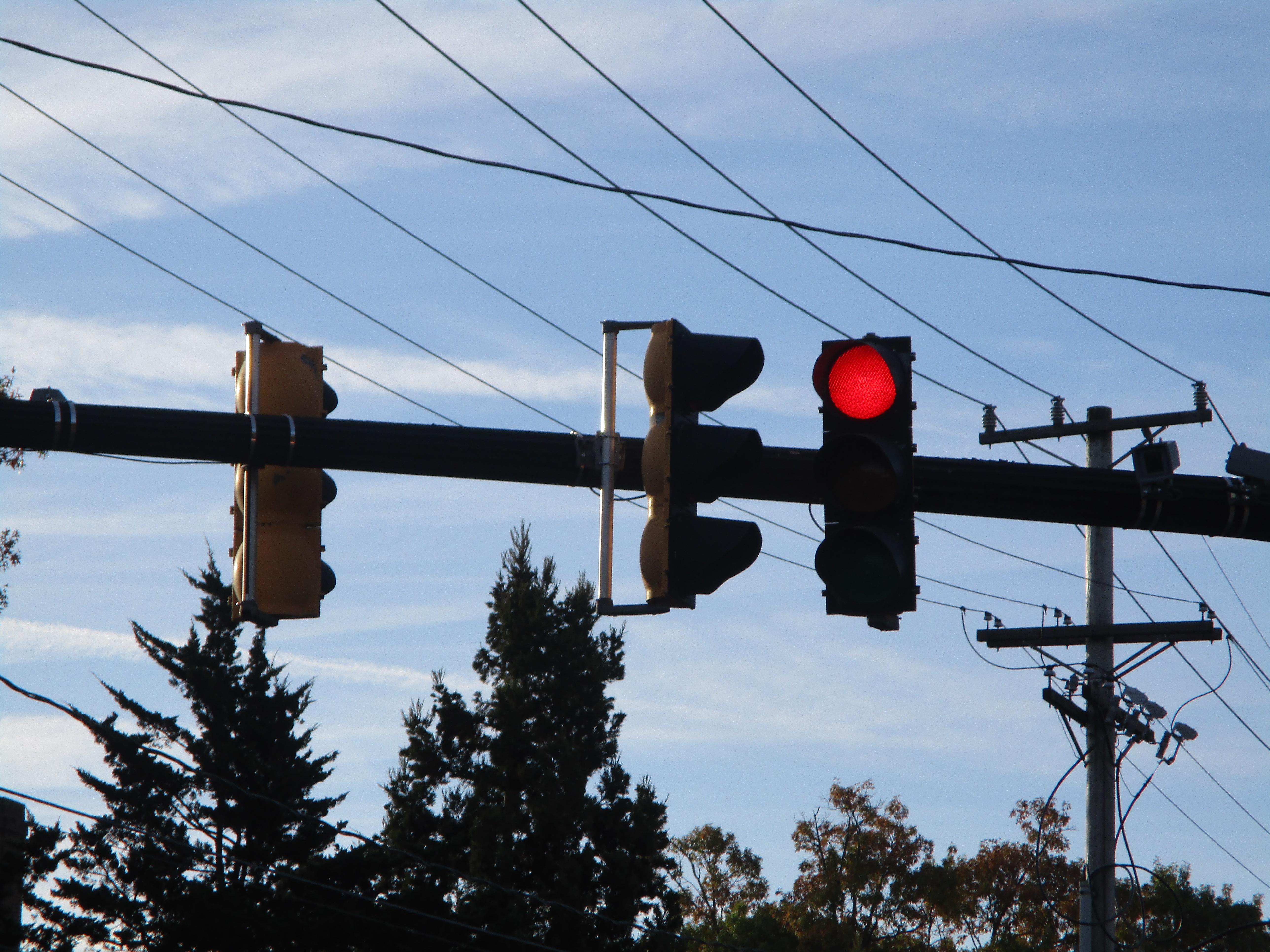 A photo of three stoplights, one red, against a blue sky.