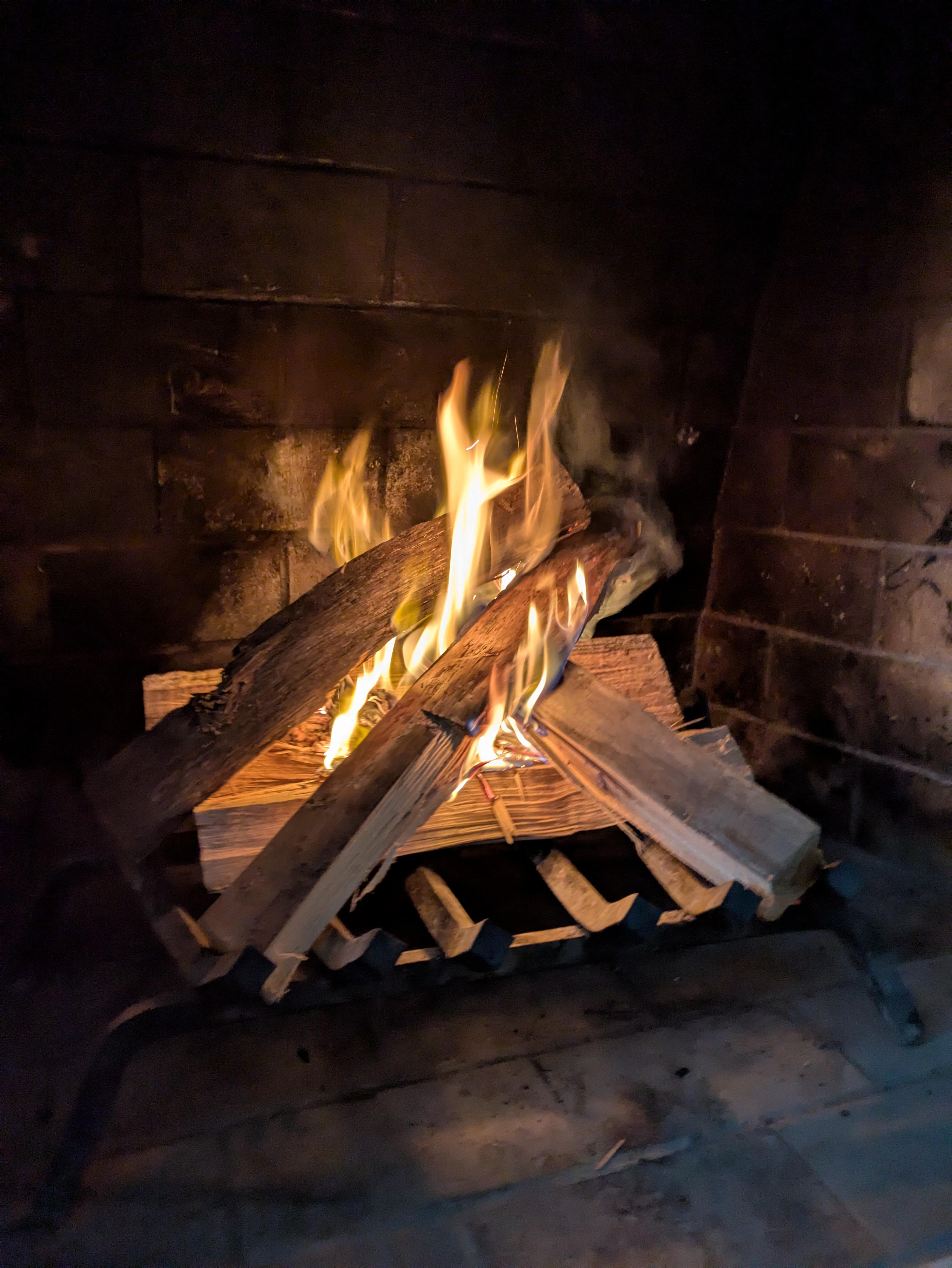 A fire roaring in an ashy fireplace.